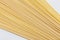 Bunch of raw linguine pasta spread on white background