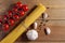 Bunch of raw spaghetti tied with rope, tomatoes cherry, bulb and slices of garlic and pepper on brown wooden background. Top view