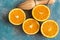 Bunch of ripe colorful oranges sliced in half with wood reamer on blue background, top view