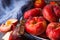 Bunch of ripe organic colorful red saturn peaches on white plate, halved, knife, blue napkin