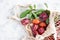 A bunch of ripe plums and a twig with leaves lie in a reusable mesh bag on a light concrete background. Fruit still life with copy