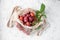 A bunch of ripe plums and a twig with leaves lie in a reusable mesh bag on a light concrete background. Fruit still life with copy