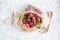 A bunch of ripe plums and a twig with leaves lie in a reusable mesh bag on a light concrete background. Fruit still life with copy