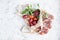 A bunch of ripe plums and a twig with leaves lie in a reusable mesh bag on a light concrete background. Fruit still life with copy