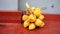 A bunch of ripe yellow coconuts, just plucked from a palm tree, lies on a red blind area near the house.