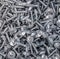 A bunch of shiny screws lies in a chaotic manner