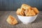 Bunch Of Small Square Sesame Puff Pastry Zu-Zu In White Porcelain Bowl Set On Wooden Table Surface