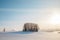 A bunch of trees in the middle of snow field under the blue vanilla sky on sunset.