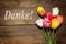 Bunch of tulips on wooden background and german word Thank you