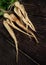 Bunch of white parsnip roots on dark wooden board