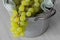 Bunch of white seedless grapes on a green tea towel  in a metal bucket container.