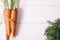 Bunch of young carrots with green tops on white wooden vintage table, healthy food on mock up background top view