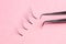 Bunches of fake lashes and tweezers on pink background. Eyelash extension procedure