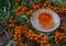 Bunches of ripe, orange sea-buckthorn on branches with sea-buckthorn oil