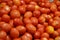 Bunches of ripe red tomatoes laying in a fruit box ready for sale at farmers market. Tomato with tails background. Closeup shot of