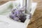 Bundeled bunch of lavender stems on a white tray on wooden table.