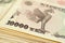 A bundle of 10000 yen Japanese bills. The reverse of the banknote with the image of the Phoenix bird close-up. Illustration on the