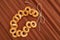 A bundle of bagels on a thread, lying on brown corrugated paper.