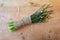 Bundle of large chives bound in burlap and tied with twine on a weathered wood background