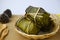 bundled boiled rice banana and sticky rice wrapped in banana leaves and black bean paste on bamboo baskets on background.Thai food