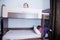Bunk bed in child room.two little girl playing on bed. chocolate shade in the interior with white walls