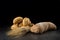 Buns and ciabatta, bread on dark wooden table. Barley and fresh mixed breads isolated on black background