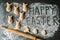 Buns in the form of Easter bunnies, rolling pin, flour and a happy Easter wish written by hand on flour on a dark background.