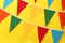 Bunting with colorful triangular flags on yellow background. Festive decor