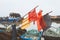 Buoy flag makers on poles above rope and fishing next baskets in Whitstable harbour. Fisherman huts and fishing boats can be seen