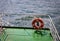 Buoy or lifebuoy ring on shipboard in evening sea. Flotation device on ship side on seascape. Safety, rescue, life preserver.