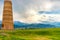 Burana tower in Balasagun, Kyrgyzstan. Landscape against the backdrop of the Tien Shan mountains covered with rain clouds