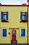 Burano, Italy - February 2019: Beautifu and yellow house in Burano, blue windows details and red door