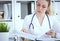 Bureaucracy in the hospital. Young female doctor work with stacks of files.