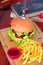 Burger with beef, salad, lettuce, french fries, and ketchup with knife on wooden board.