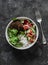 Burger bowl. Beef patty with rice and fresh vegetable salad on a dark background, top view