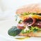 Burger ciabatta with smoked sausage, fresh salad mix, tomatoes, pesto sauce and onions