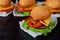 Burger with falafel, salad, onion rings, cheese, tomatoes and chili pepper on the black background. Classic american fast food