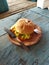 burger food stuffed with meat, cheese, onions, tomatoes, salad with a beachside cafe background