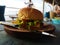 burger food stuffed with meat, cheese, onions, tomatoes, salad with a beachside cafe background