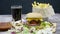 Burger, french fries, cola and ketchup on wooden table over black background