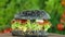 Burger or hamburger with black bread on a blurred background of leaves of lettuce and vegetables lay on a wooden board