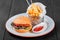 Burger, hamburger with french fries, ketchup, mayonnaise, fresh vegetables and cheese on plate on dark wooden background.