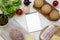 Burger ingredients and blank notepad on white wooden background, overhead view. Flat lay, from above, top view