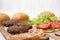 Burger ingredients on a white wooden surface, side view. Close-up