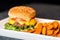 Burger meal on plate. Delicious hamburger with juicy beef, melting cheddar cheese served with crispy sweet potato fries.