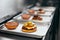 Burger Restaurant. Closeup Of Burgers Cooking In Kitchen