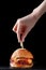 Burger with skewer on wood. female hands hold skewer