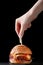 Burger with skewer on wood. female hands hold skewer