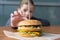 Burger on the table, in the background a girl reaches out to take a sandwich