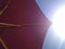 Burgundy beach umbrella against the sky and the scorching sun